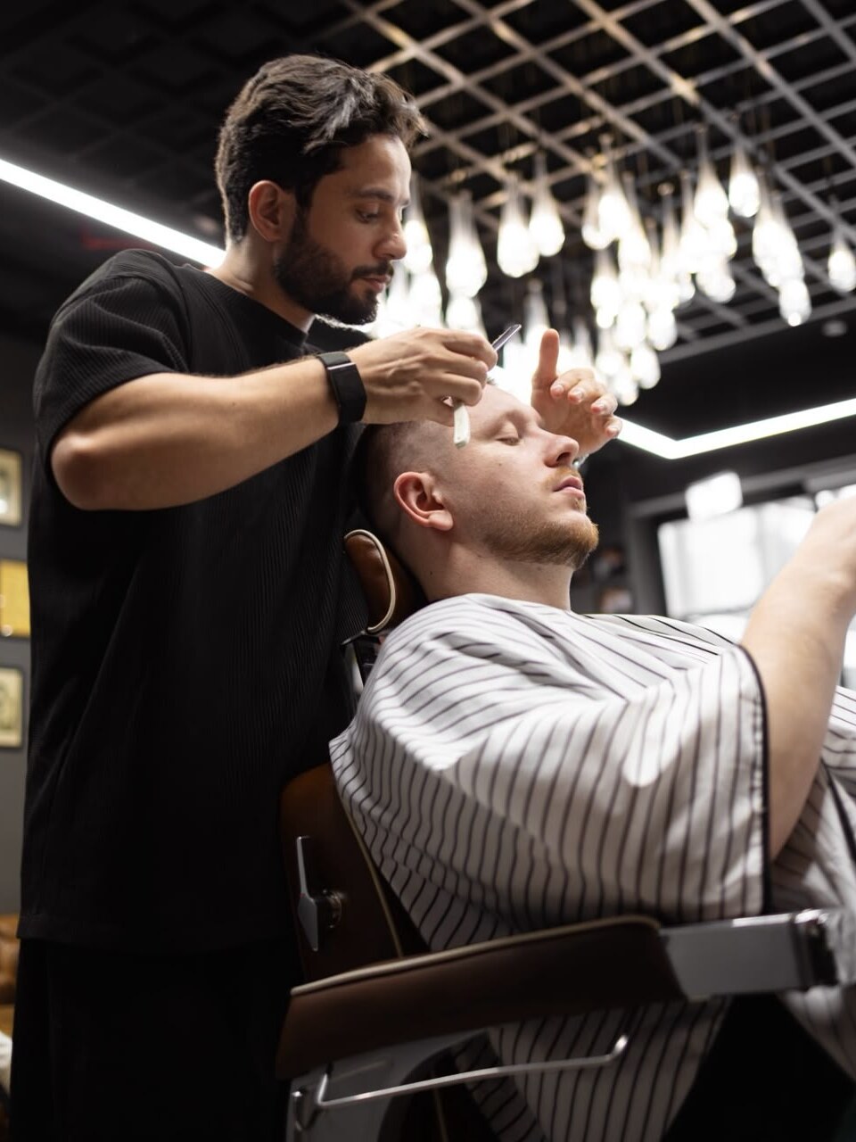 The barber finishing a client's cut with a straight razor
